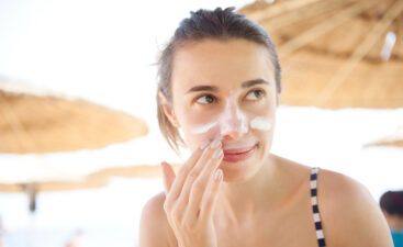 beautiful woman smears face sunscreen at the beach for protection.