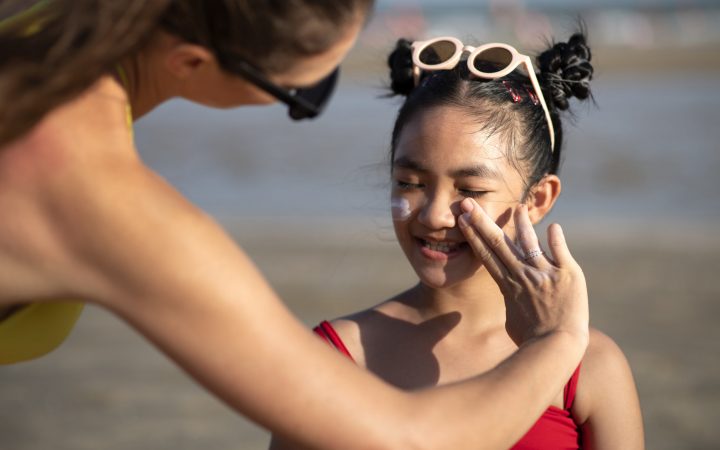 woman-applying-sunscreen-kid-front-view